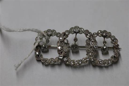 A 1920s white gold and diamond set interlocking triple circle openwork drop brooch,